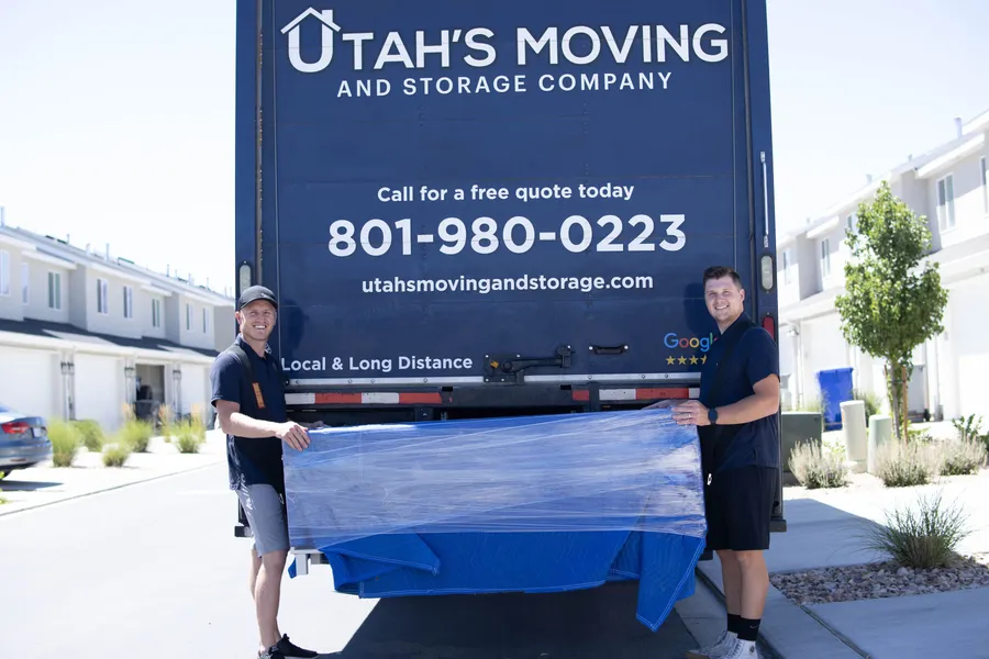 Utah's Moving & Storage crew posing with wrapped furniture at the branded truck