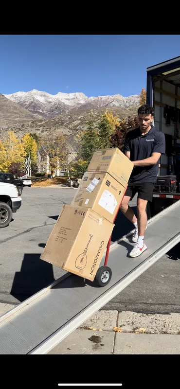 Utah's Moving & Storage crew member unloading boxes from the moving truck ramp with Utah mountains in the background