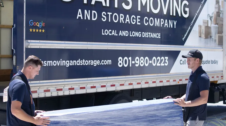 Utah's Moving & Storage crew carrying wrapped furniture for a long-distance move