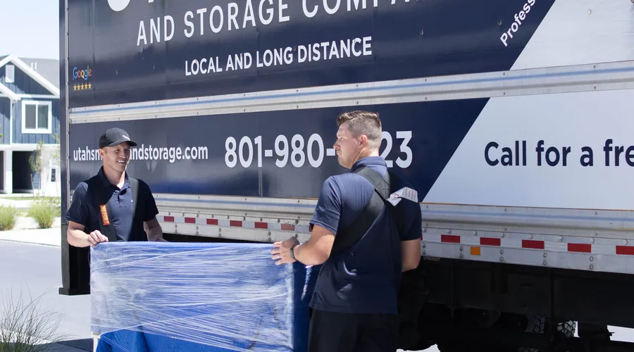 Crew carrying wrapped furniture next to the branded moving truck